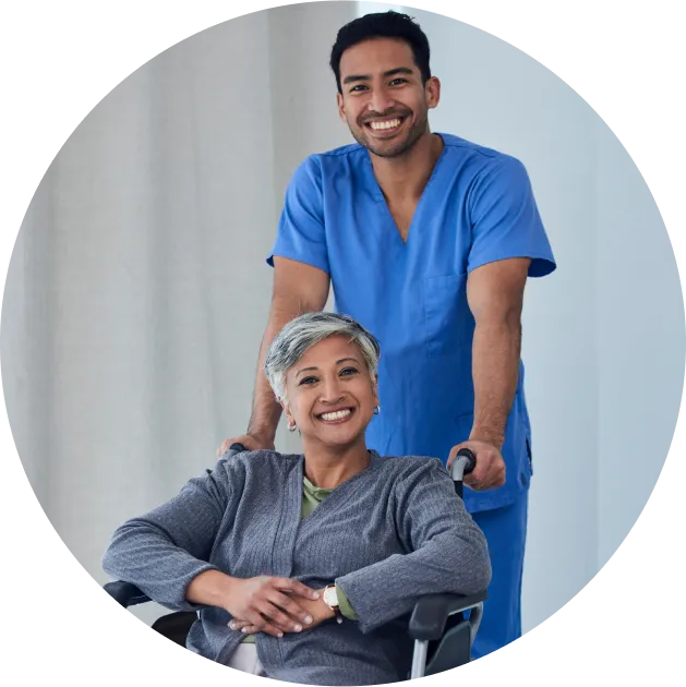 Smiling male doctor standing with an elderly woman in a wheelchair, symbolizing compassion and professional care.